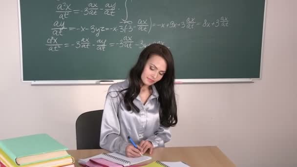 Menina senta-se à mesa e pishit em um caderno, levanta-se e sai da sala de aula . — Vídeo de Stock