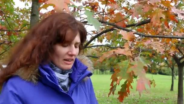 Frau pustet sich im Herbstpark die Nase aus. — Stockvideo