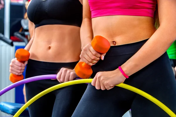 Vientre femenino desnudo con pesas y aro en el gimnasio . — Foto de Stock