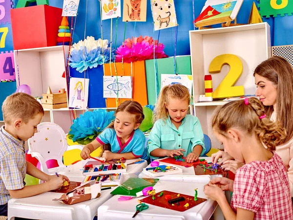 Kids holding colored paper and glue on table in kindergarten . — Stock Photo, Image