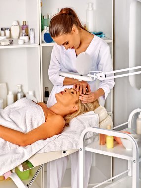 Spa salonda orta yaşlı kadın. Güzellik uzmanı tarafından tweezing kaş.