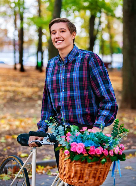 공원에 꽃 바구니와 함께 자전거에 남자. — 스톡 사진