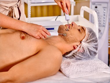 Man receiving electric facial peeling hydradermie massage. clipart