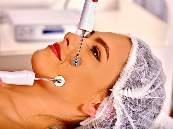 Mujer joven recibiendo masaje facial eléctrico . —  Fotos de Stock