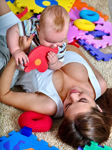 Kid pojke med mor kryssade pussel leksak på golvet. — Stockfoto