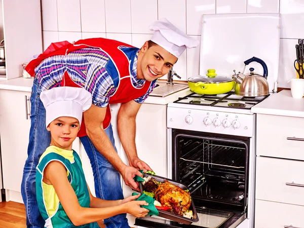 Pai e filho cozinhar frango na cozinha . — Fotografia de Stock