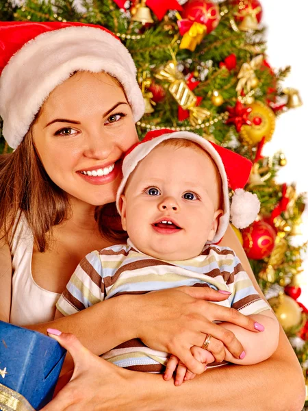 Μαμά φορώντας Santa καπέλο εκμετάλλευση μωρό κάτω από το χριστουγεννιάτικο δέντρο. — Φωτογραφία Αρχείου