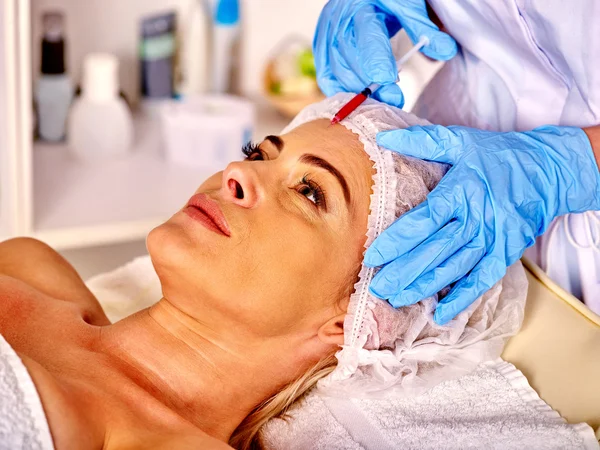 Kvinna medelålders i spasalong med kosmetolog. Kvinnliga ger botox injektioner. — Stockfoto