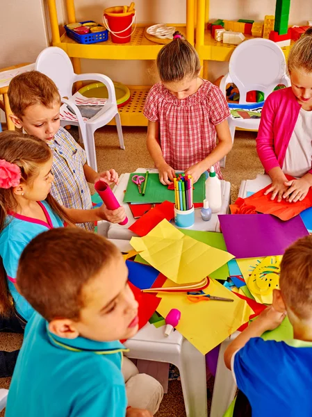 Kids holding colored paper on table — Stock Photo, Image