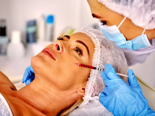 Kvinna medelålders i spasalong med kosmetolog. Kvinnliga ger botox injektioner. — Stockfoto