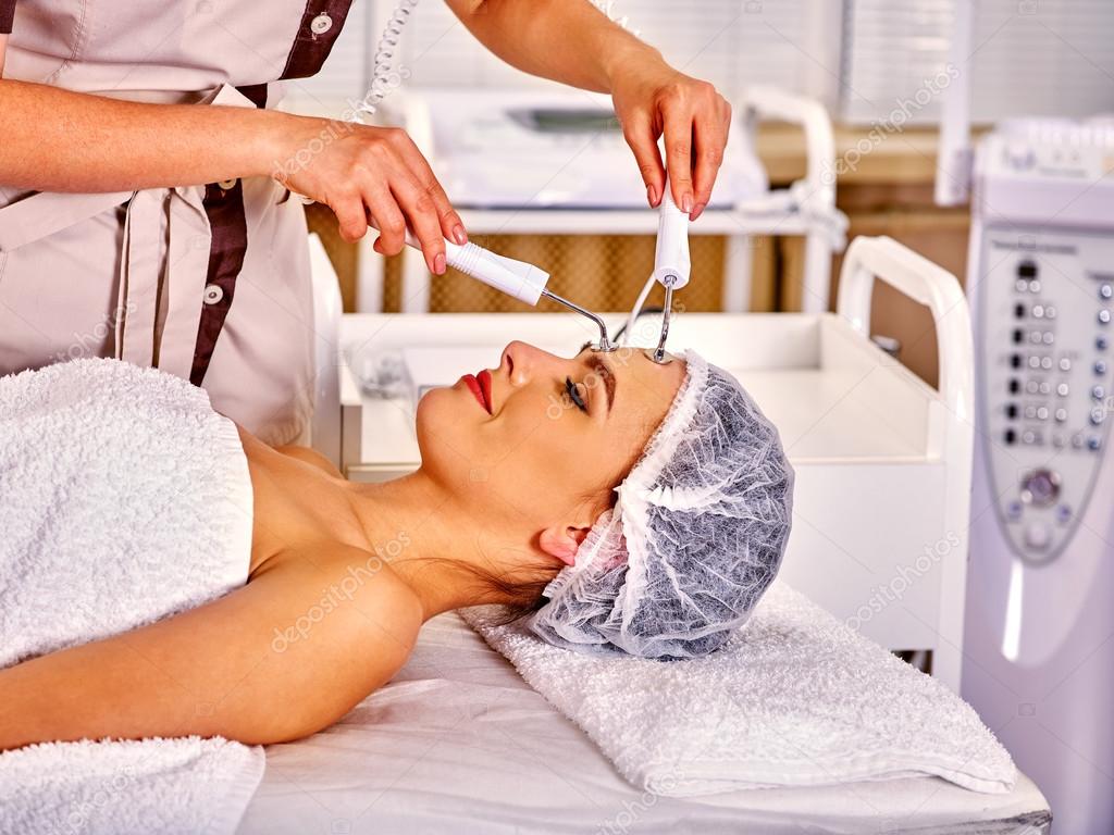 Young woman receiving electric facial massage.