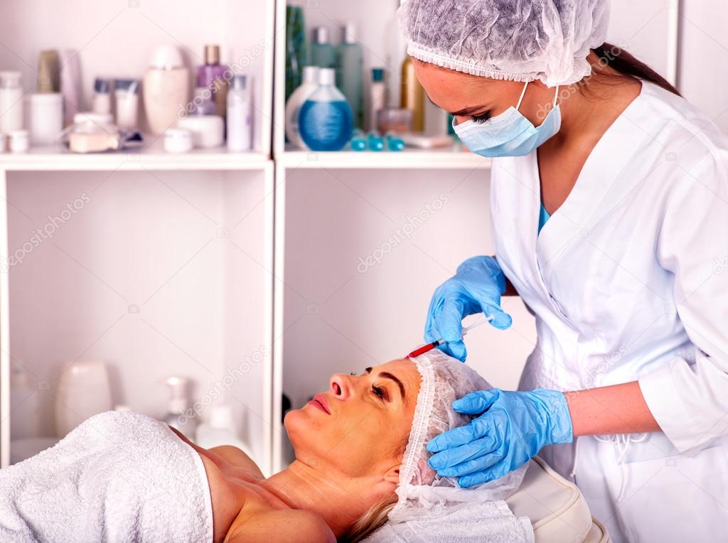Woman middle-aged in spa salon with beautician. Female giving botox injections.