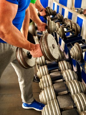 Kollarını dumbbells ile spor salonunda çalışan adam.