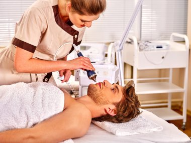 Genç kadın elektrik yüz masajı alma.