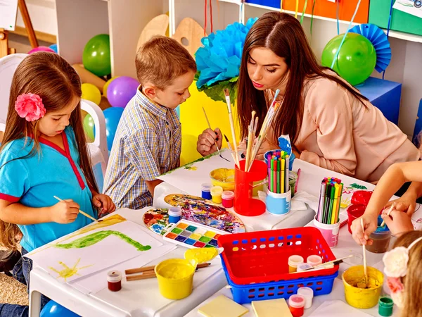 Niños con maestra pintando sobre papel en el jardín de infantes  . —  Fotos de Stock