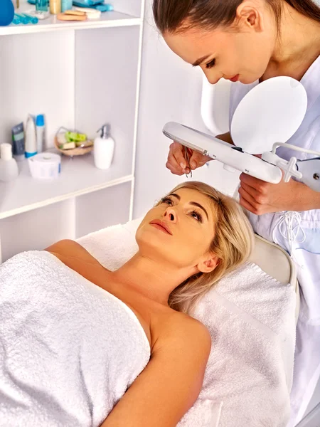 Woman middle-aged in spa salon. Tweezing eyebrow by beautician. — Stock Photo, Image