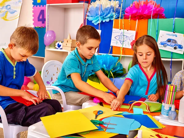 孩子们在幼儿园的桌子上拿着彩色纸 . — 图库照片