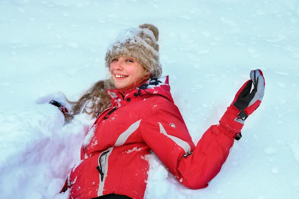 Menina vestindo roupas de inverno deitado na neve  . — Fotografia de Stock