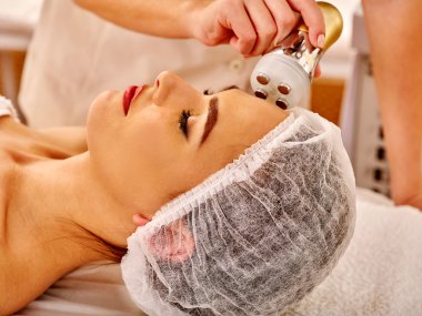 Genç kadın elektrik yüz masajı alma.