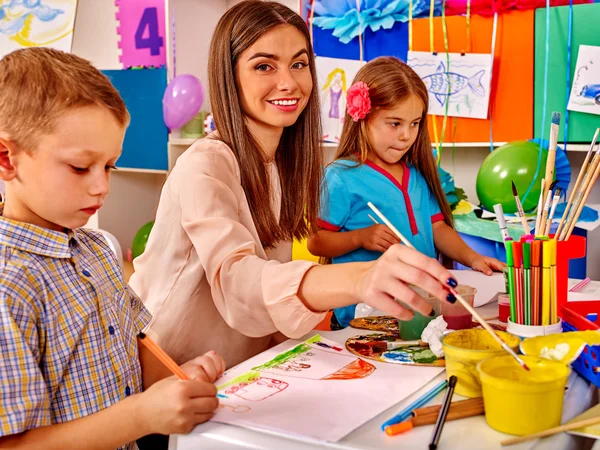 Niños con el profesor pintando sobre papel — Foto de Stock