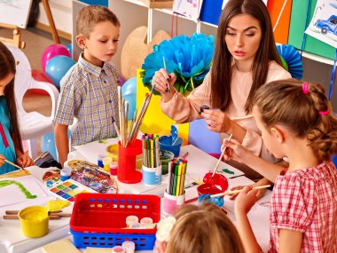 Öğretmen craft kağıt üzerinde olan çocuklar