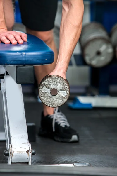 Mann arbeitet im Fitnessstudio mit Hanteln an den Armen. — Stockfoto