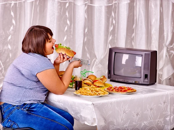 Vrouw eten fastfood en het kijken naar tv. — Stockfoto