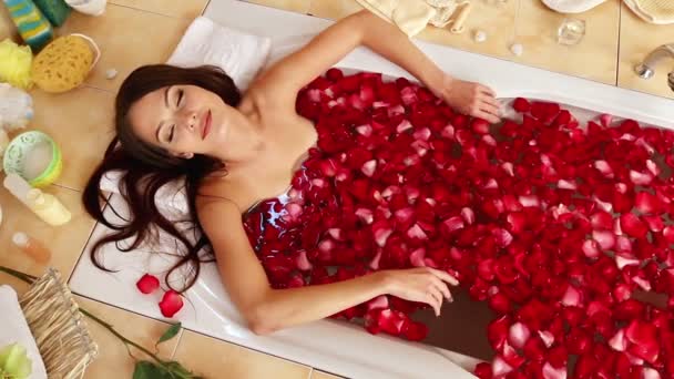 Fiatal nő egy pihentető, rózsaszirom fürdő spa szalon. — Stock videók