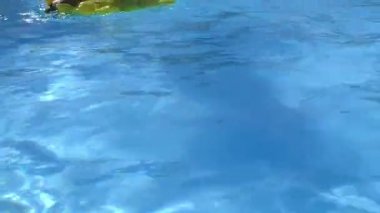 Şişme halkada yüzen giyen çocuk güneş gözlüğü havuzunda yüzüyor.