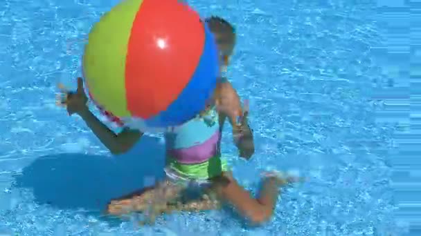 Child girl playing with beach ball in blue water. — Stock Video