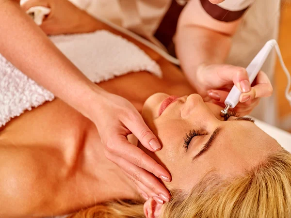 Mujer joven recibiendo masaje facial eléctrico . — Foto de Stock