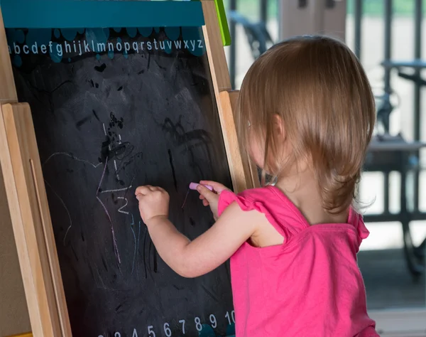Mladá holčička kreslení na tabuli — Stock fotografie