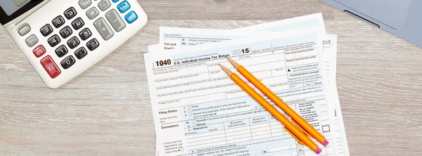 Laptop ve hesap makinesi üzerinde 2015 IRS form 1040 — Stok fotoğraf