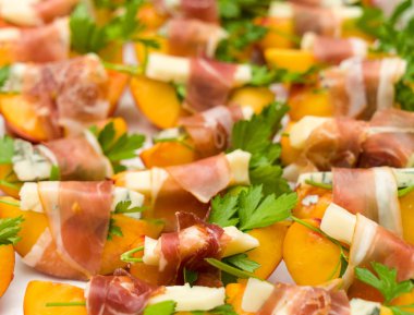 Birçok küçük şeftali ve gorgonzola prosciutto aperatifler sarılmış