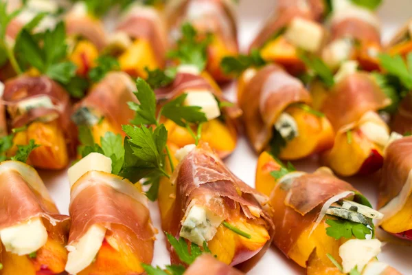 Muitos pequenos lanches de pêssego e gorgonzola envoltos prosciutto — Fotografia de Stock