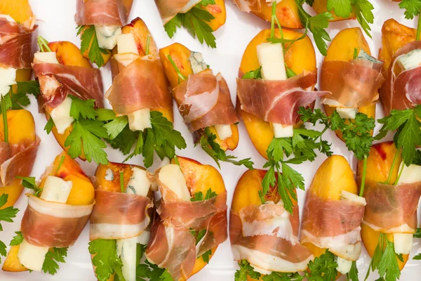 Muitos pequenos lanches de pêssego e gorgonzola envoltos prosciutto — Fotografia de Stock