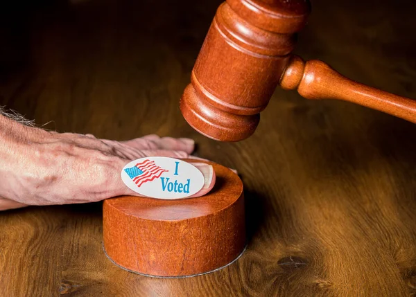 I voted campaign button or sticker on hand with a gavel and mallet to illustrate lawsuits about voting