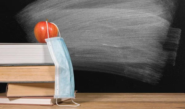 마스크를 쓴 책과 사과가 쌓여 있는 가상의 학교 배경 개념으로 돌아가서 — 스톡 사진