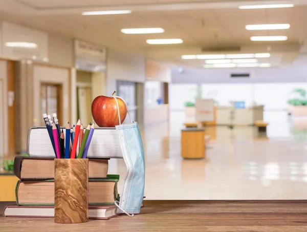 教科書、鉛筆、フェイスマスク付きリンゴのスタックと学校の背景の概念に戻る — ストック写真