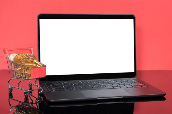 Komputer laptop modern dengan keranjang belanja penuh dengan koin emas — Stok Foto