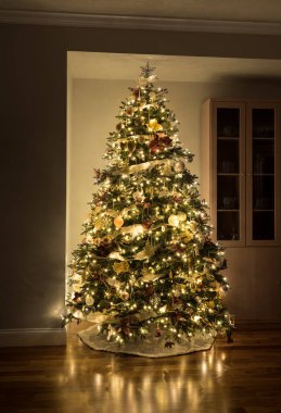 Modern bir oturma odasının köşesinde süslü bir Noel ağacı.