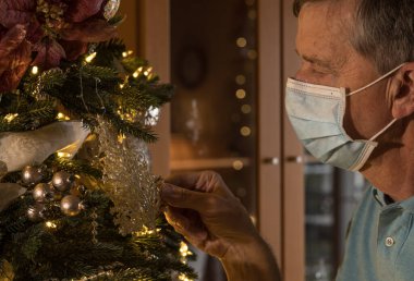 Kıdemli yetişkin adam elinde bir noel süsü tutarak geçmişi hatırlıyor.