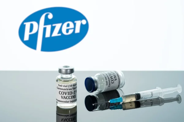 Covid-19 vaccin i injektionsflaska med spruta reflekterad mot vit Pfizer bakgrund — Stockfoto