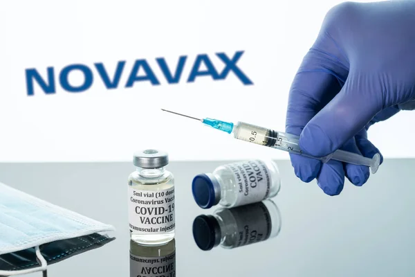 Vacuna de Covid-19 en vial con jeringa reflejada contra el logotipo de Novavax sobre fondo blanco —  Fotos de Stock