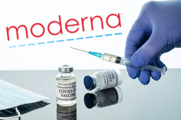 Covid-19 vaccin i injektionsflaska med spruta reflekterad mot Moderna logotypen på vit bakgrund — Stockfoto