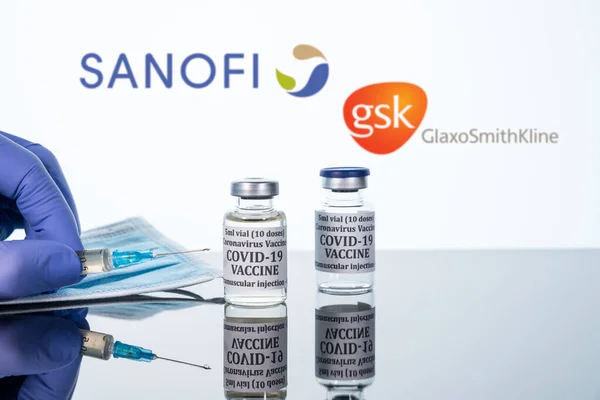 Covid-19 vaccine in vial with syringe reflected against white Sanofi GSK background — Stock Photo, Image