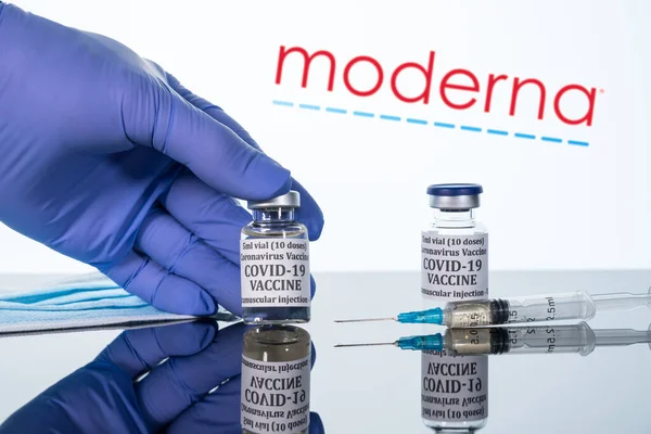 Covid-19 vaccine in vial with syringe reflected against Moderna logo on white background — Stock Photo, Image