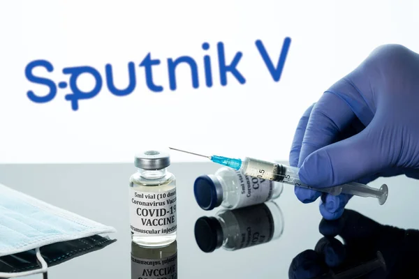 Covid-19 vaccine in vial with syringe reflected against white Sputnik logo background — Stock Photo, Image