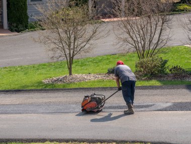İşçi asfalt caddesini onarmak için fazladan asfalt takıyor
