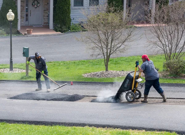 Trabajadores aplicando blacktop extra para reparar calle asfaltada — Foto de Stock